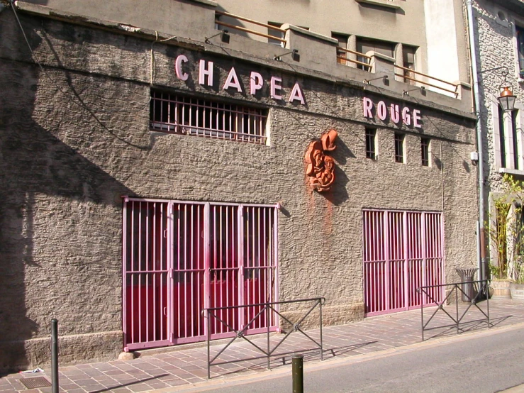 an empty street in front of a business with doors and fences