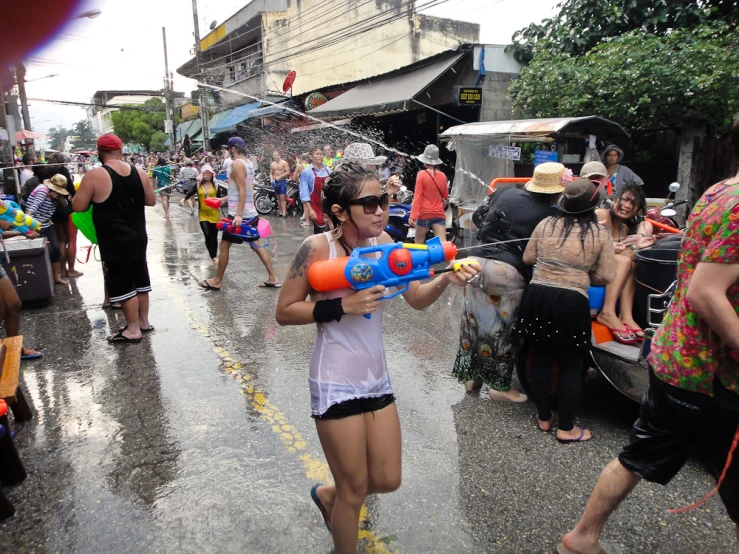 a lady wearing an eye protection sunglasses plays with a water cannon