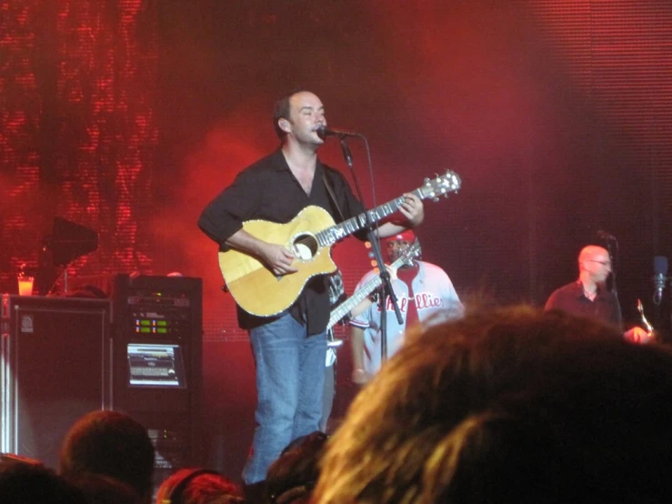 man standing on stage playing an acoustic instrument