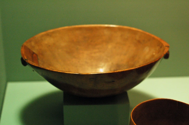 a brown bowl and a brown cup sit on a green surface