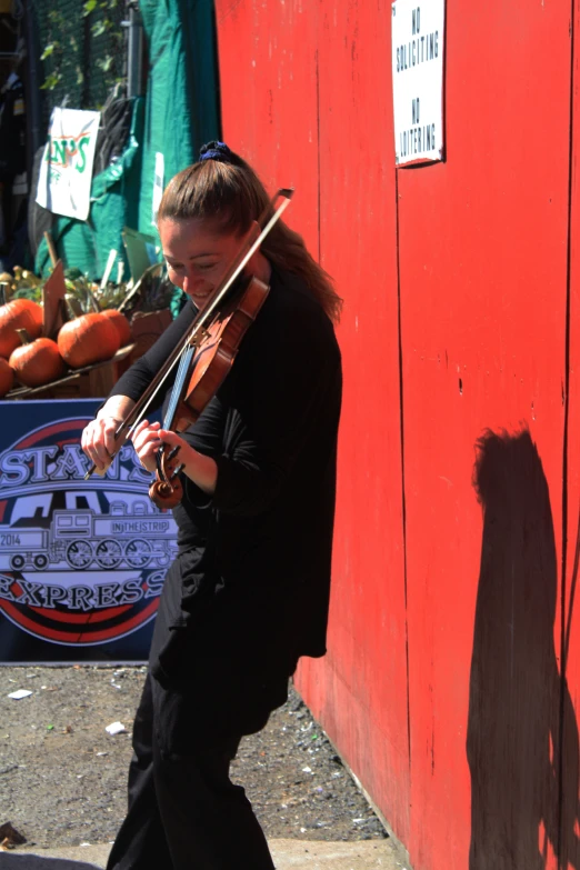 woman playing violin in front of a red wall