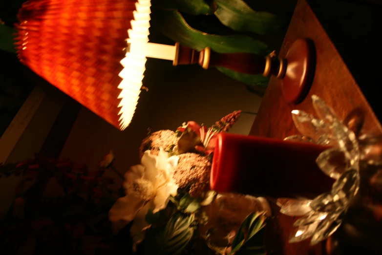 an illuminated candle is beside a table with flowers and a teddy bear on it