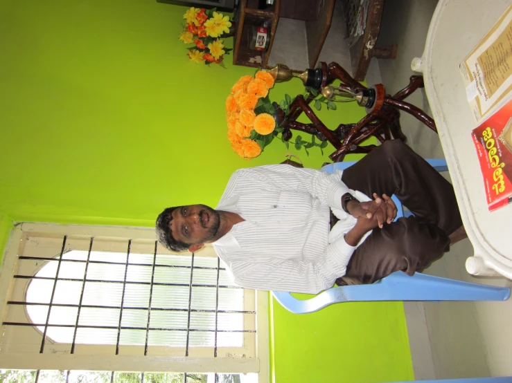 man sitting in blue chair near green painted room with flower pot