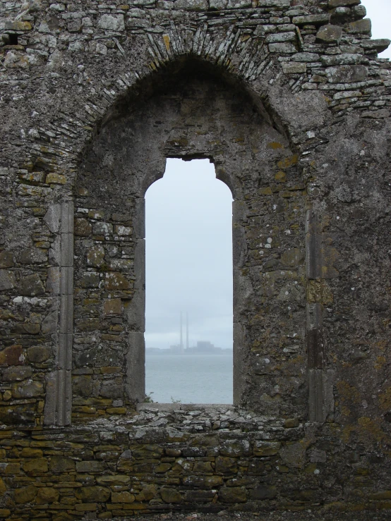 an old stone wall with some windows overlooking the ocean