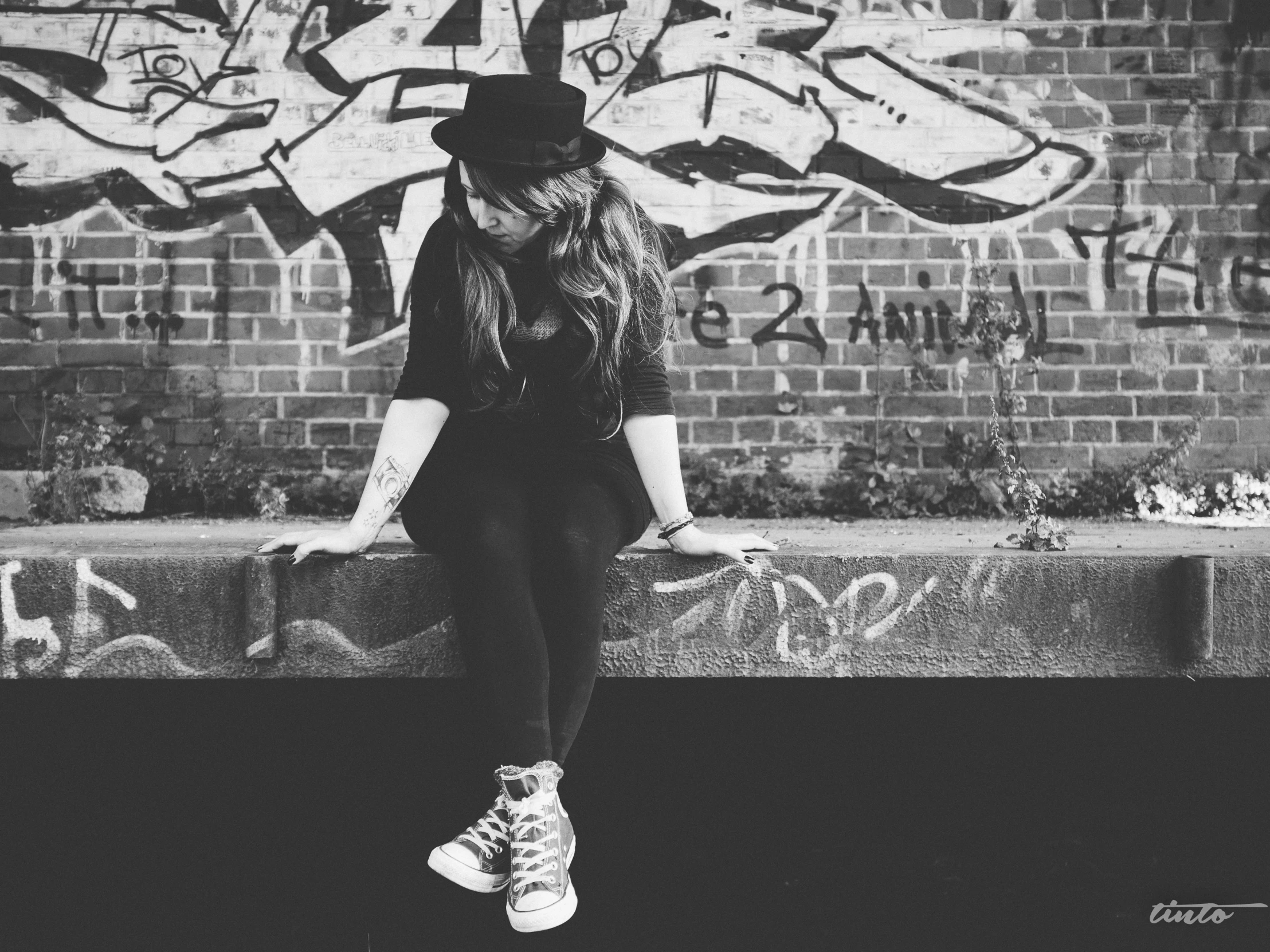 a woman sitting on top of a wall covered in graffiti