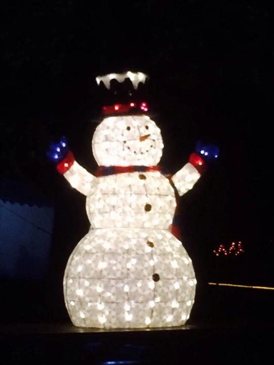 a lighted snowman in a yard at night