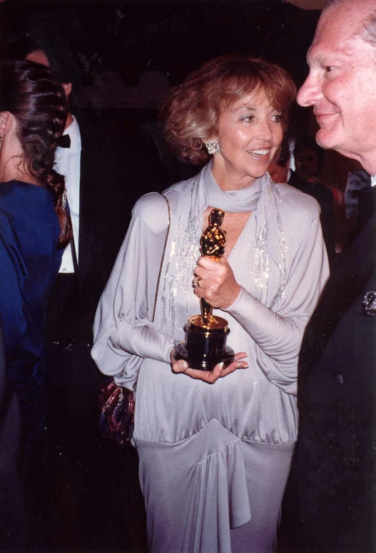 two people are standing holding a trophy