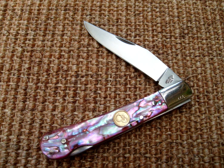 a pink and white patterned pocket knife laying on the ground
