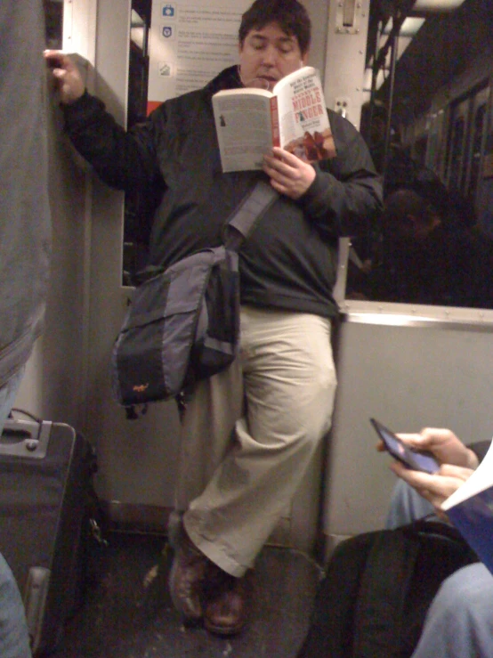 a person reading a book while riding a public transit