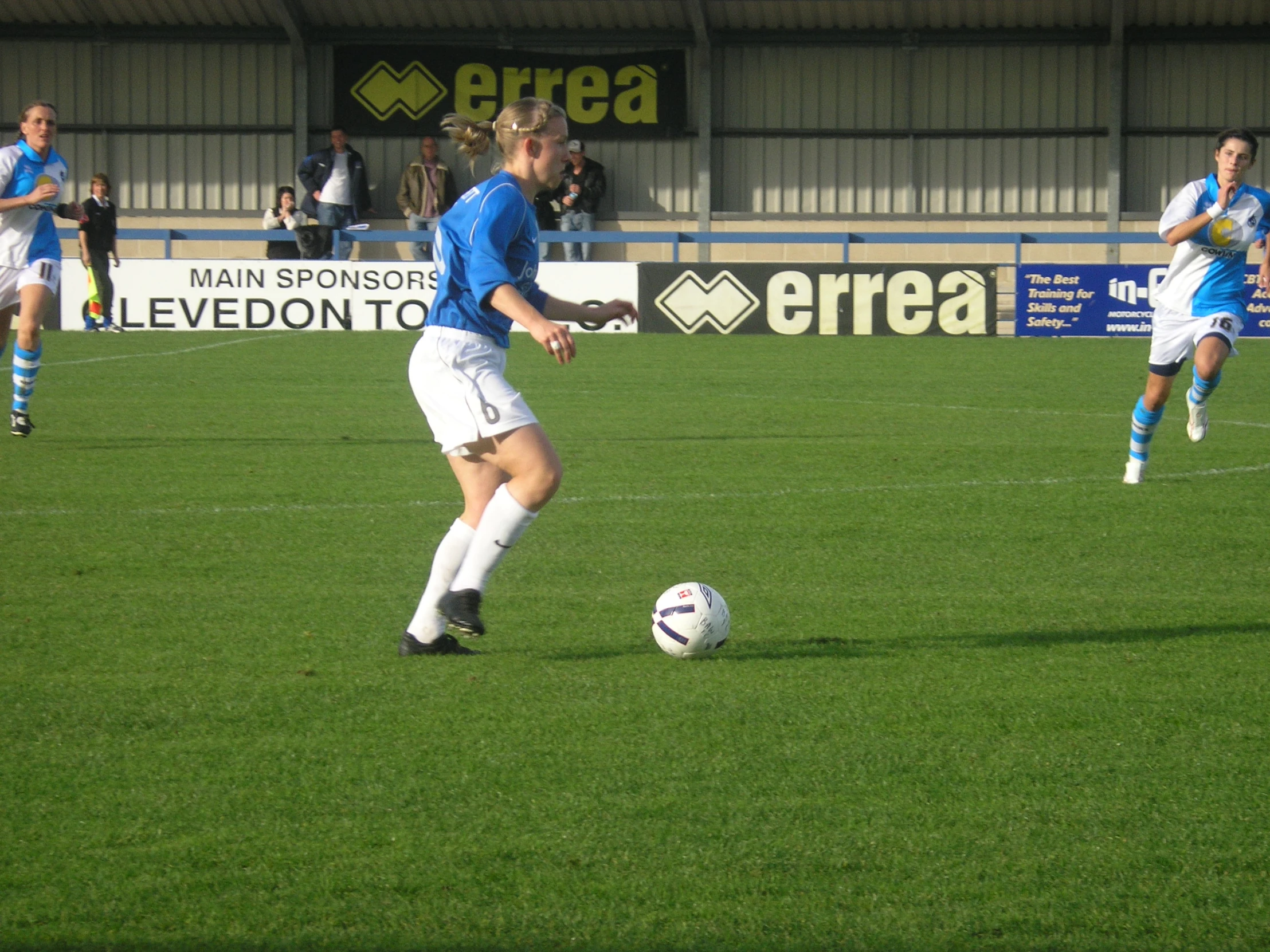 a woman in blue and white uniform kicking a soccer ball