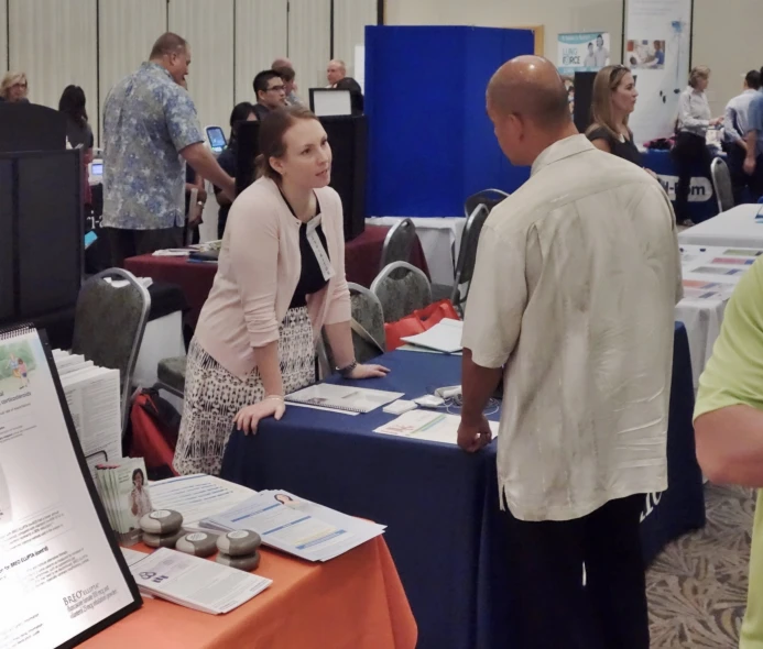 two women and one man are talking at a booth