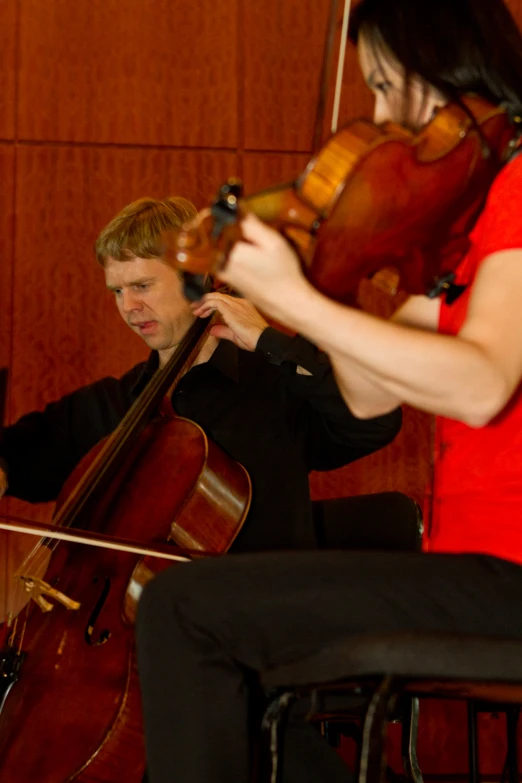 two people playing cellos with an audience