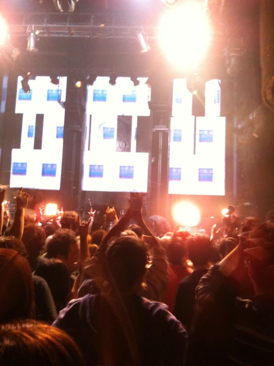 a crowd of people watching two large screens on a building