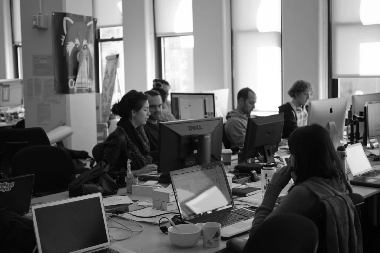 a group of people sitting around a table with computers