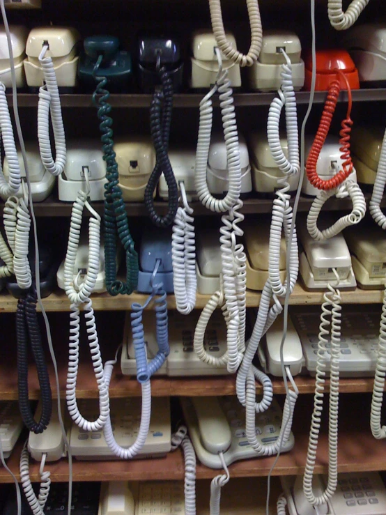 many telephone wires and telephones are on the shelf