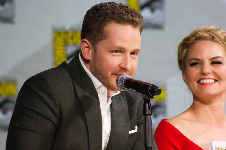 a man and a woman are posing in front of a microphone