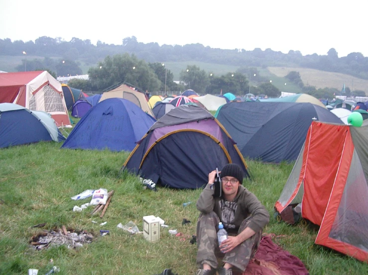 a person sits near tents in the grass