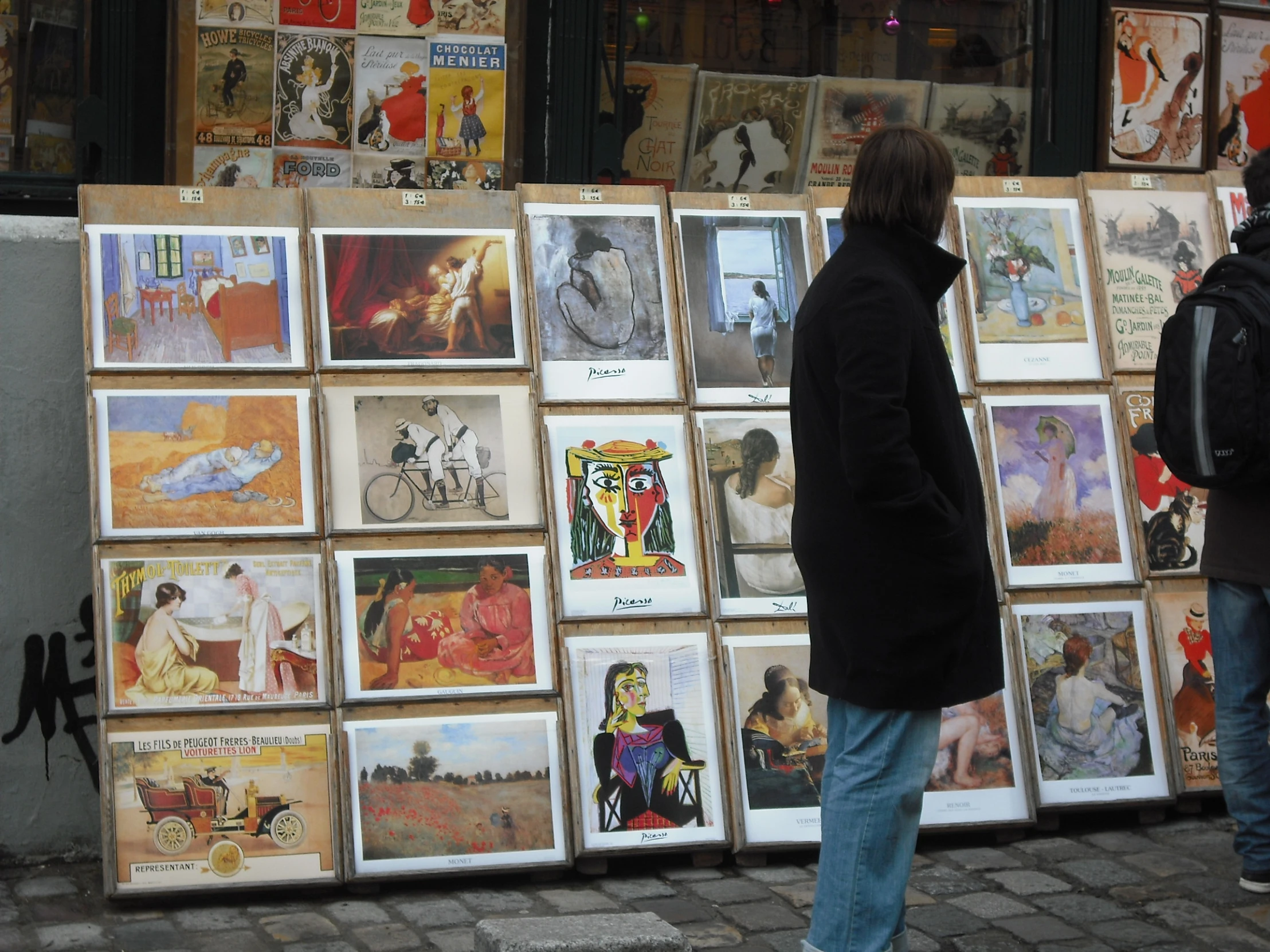 a woman walking next to a wall with a lot of pictures