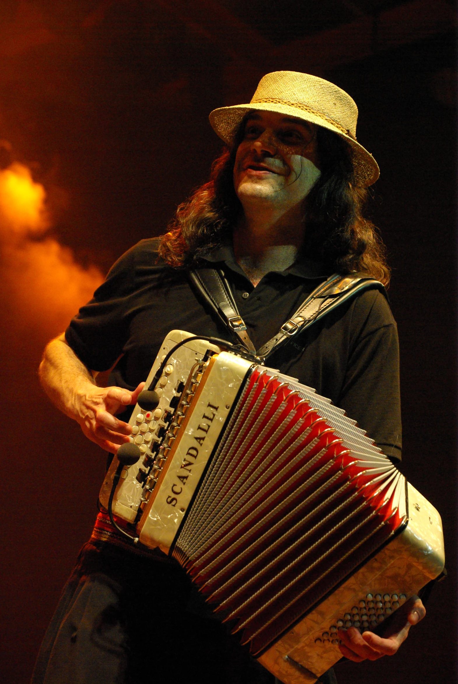 a man with long hair and a straw hat playing an accordion