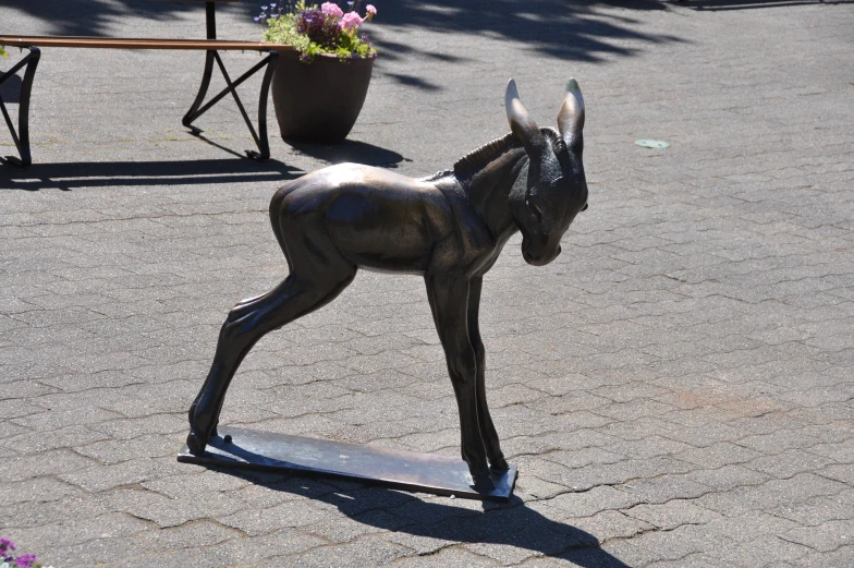 an adorable little miniature fawn looking animal statue on the street