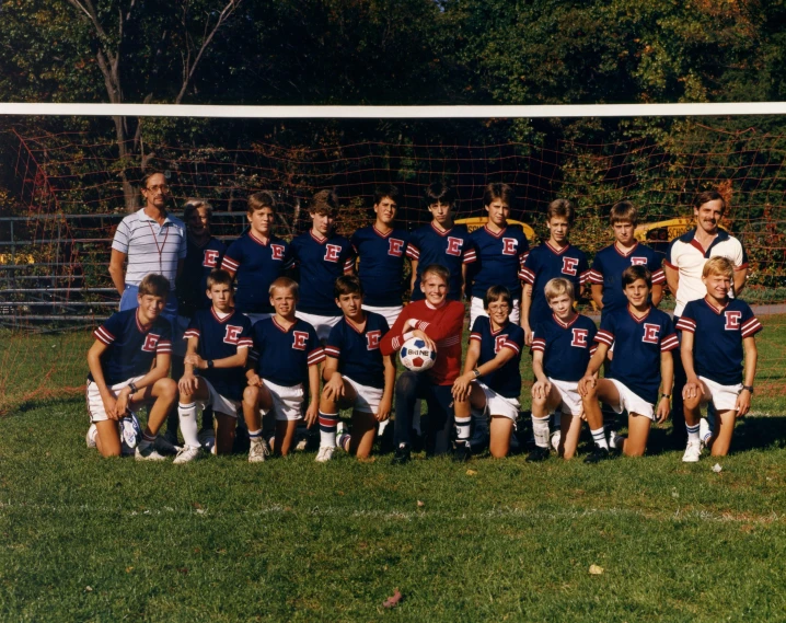 a group of children and their coaches posing with a soccer ball