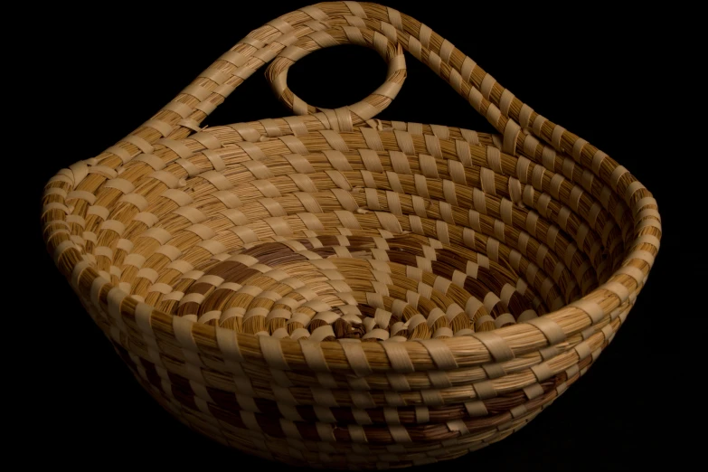 an ancient woven basket is on display in front of a black background