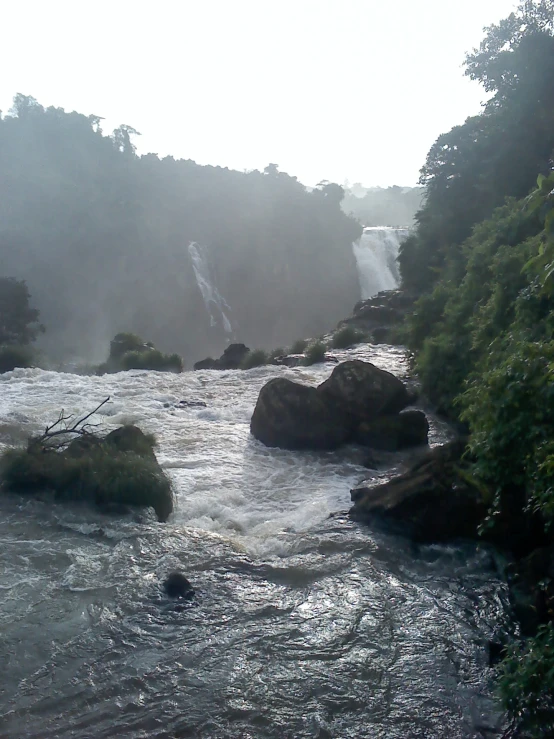 a river with waterfall in background with rocks and trees