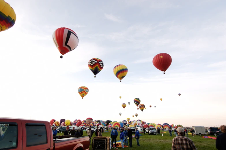 several  air balloons being flown by people near a field