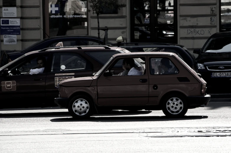 a small car driving in front of some parked cars