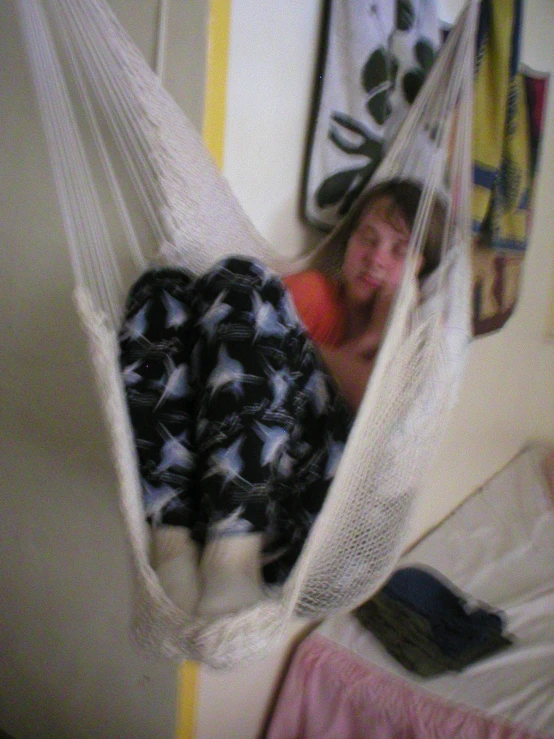 a person laying in a hammock on a bed