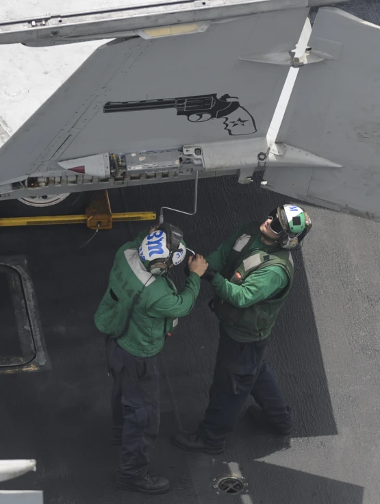 a couple of men standing next to a fighter jet