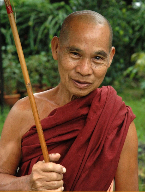 the monk with a stick poses for the camera