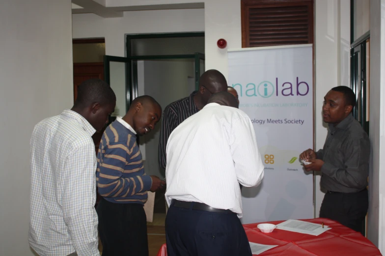 men in black shirts stand around a red table with a sign that says sataab on it