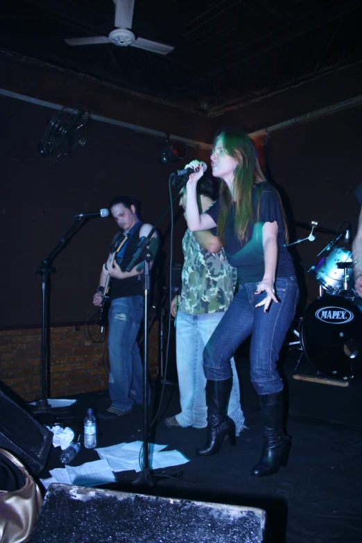 several people singing into microphones in a dark room