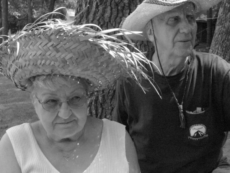 an old man and woman with hat on their heads