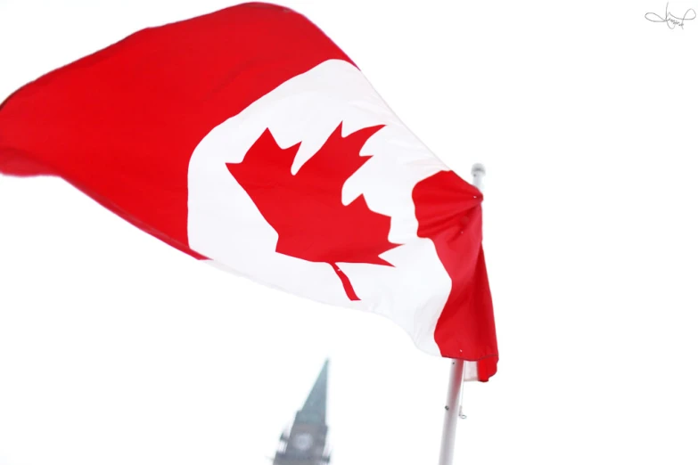the canadian flag with a spire in the background