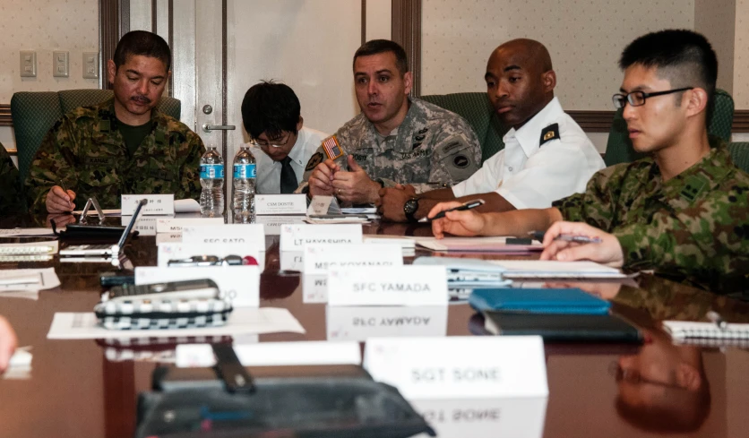 five military people sitting around a table working