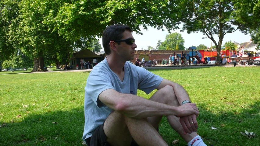 a man in sunglasses sits on the ground