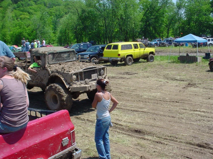 a group of people look at trucks at an obstacle course