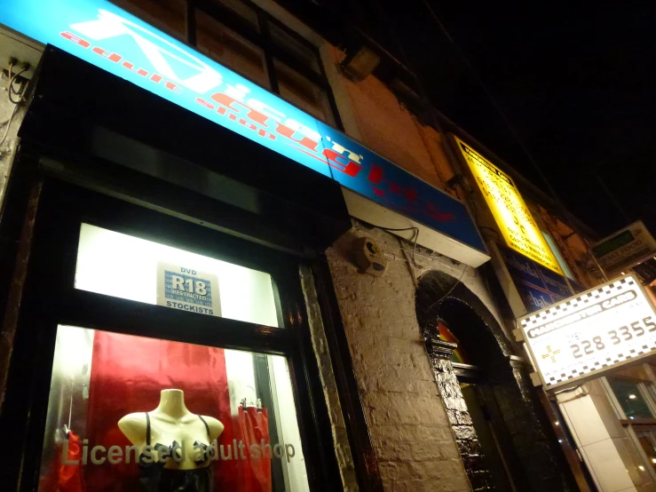 a store with neon lights and some mannequins in front of it