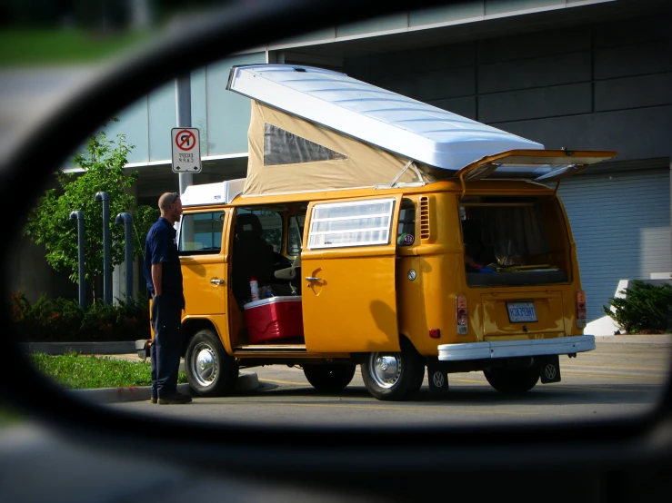 man standing outside the camper van with an orange roof