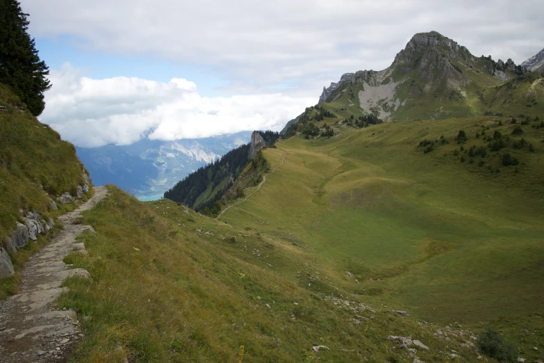 a scenic green mountain scene with a path leading into the valley