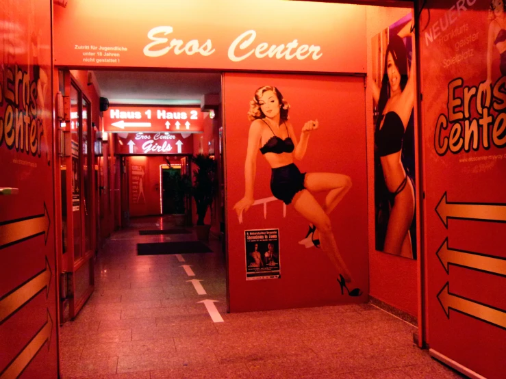 woman in a bathing suit sitting on a door handle in front of an advertit for the east central sex club