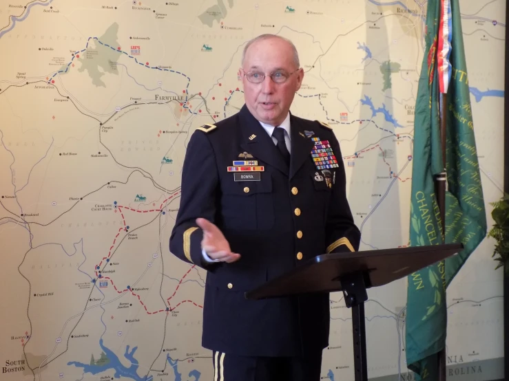 man in military uniform giving speech by map background