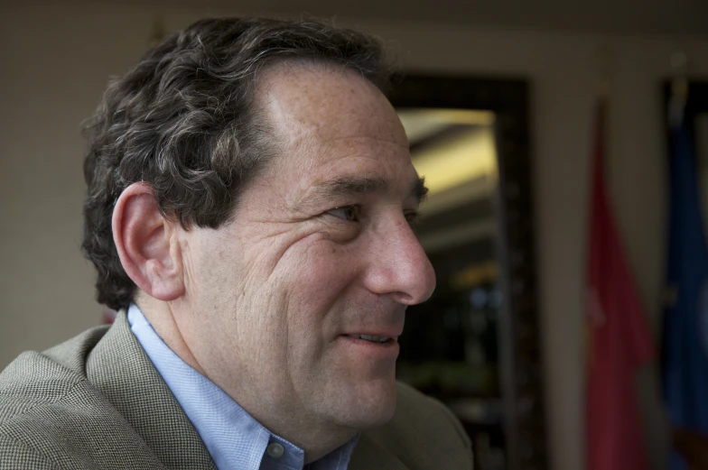 a man in a suit and tie smiles at soing