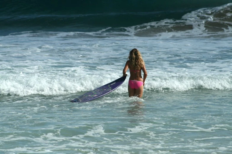 a girl standing in the ocean with a surfboard