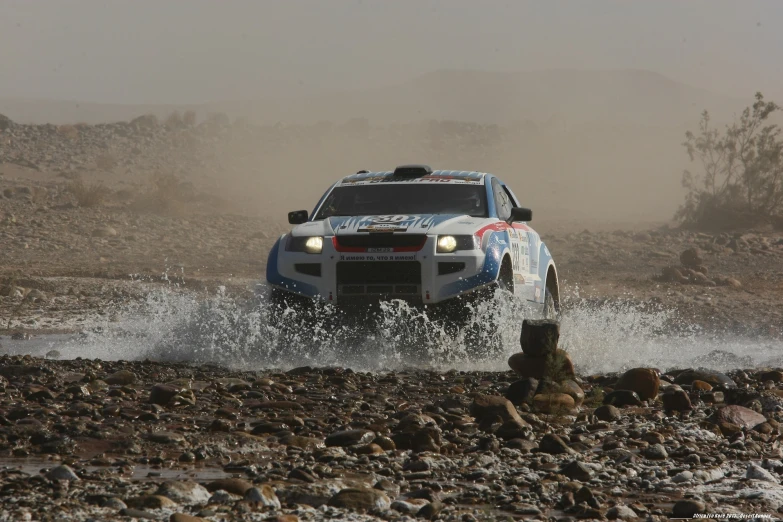 a rally car splashing through a muddy dle