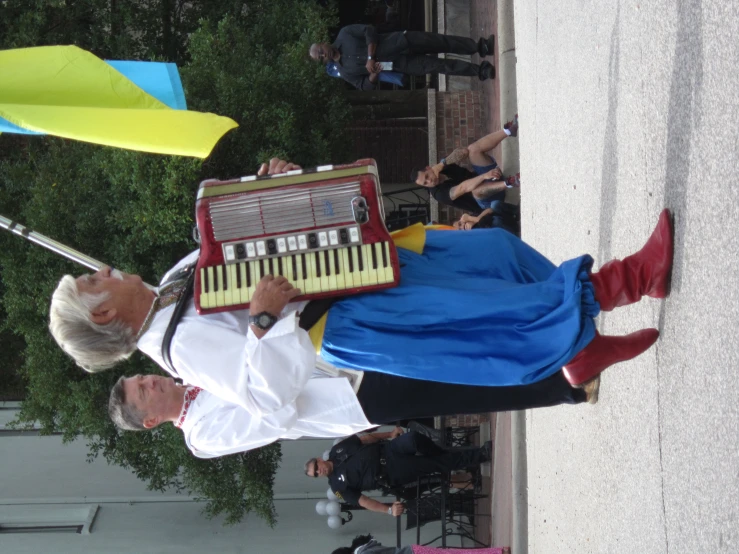 an old man plays on an accordion in the street