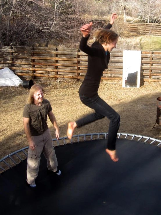 a woman jumps on a trampoline in a backyard