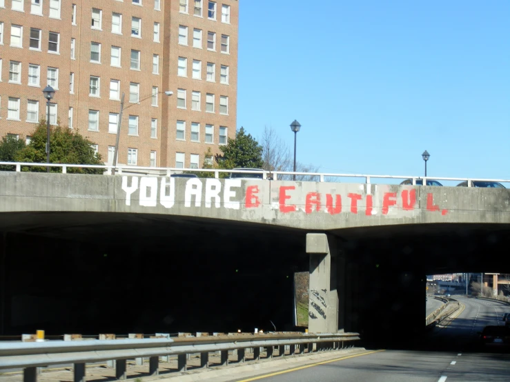 a street that has a bridge with a graffiti on the wall above it